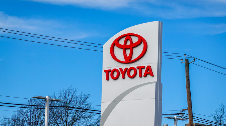 View of a large Toyota car dealership road sign showing the company logo and Toyota name in red letters