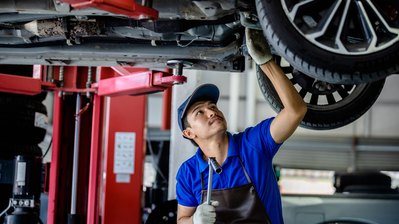 Auto mechanic repairman using a socket wrench working auto suspension repair in the garage