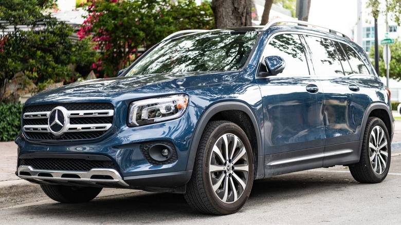 Blue Mercedes-Benz GLB SUV parked on a residential street, shown from a front three-quarter angle with trees and houses in the background