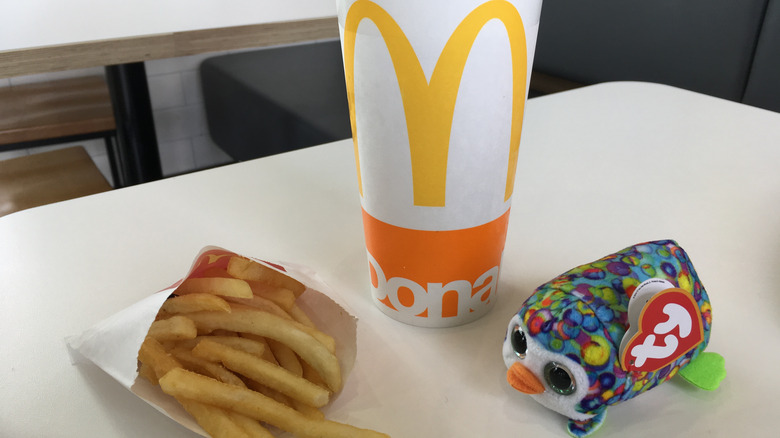 Fries, McDonald's drink, and Beanie Baby toy on table
