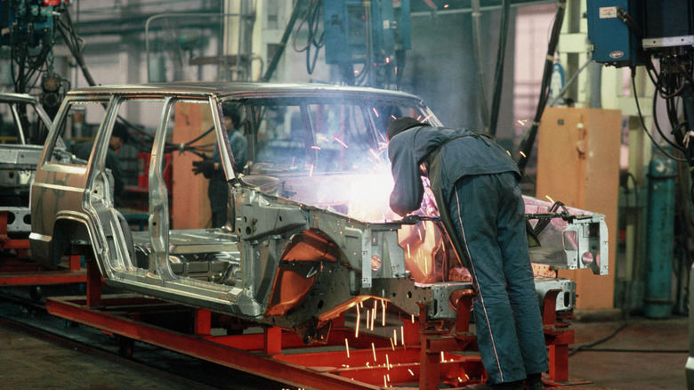 worker welding a car chassis in the 1980s