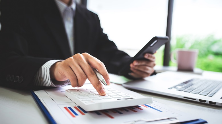a woman in an office uses a smartphone and calculator