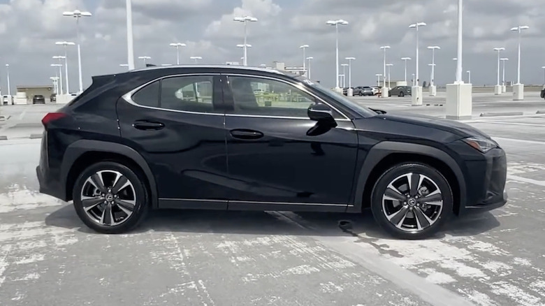 A side view of a black 2022 Lexus UX 200 parked on a cement lot on a cloudy day