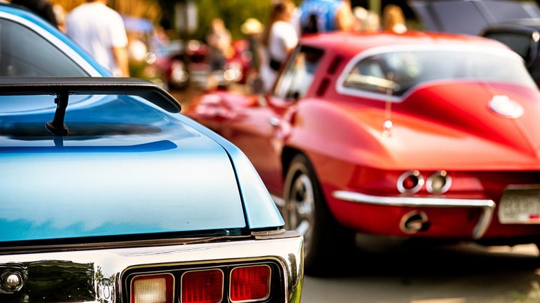 Rear view of classic 60s muscle cars at vintage automotive exhibition.
