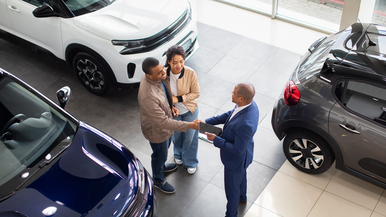 Couple talking to a salesperson at a car dealership