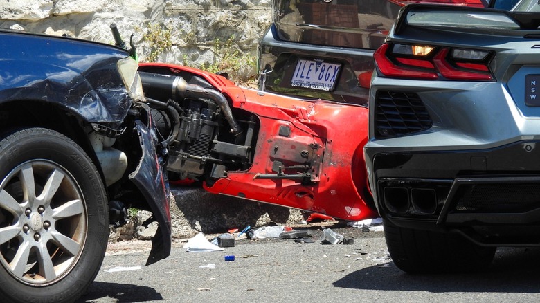 Scooter involved in a car crash with an SUV with a Volkswagen and Chevrolet sportscar in the scene