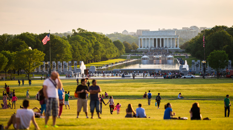 A crowd dots the National Mall on a sunny, dusky afternoon