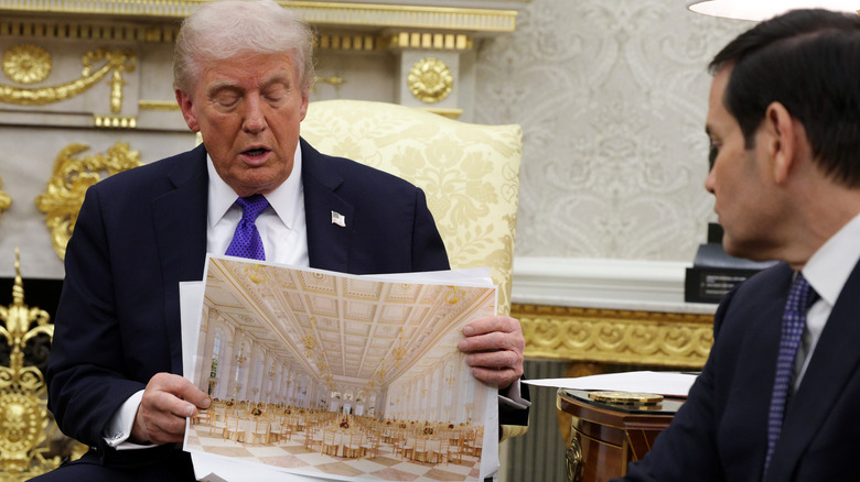 President Donald Trump holds up renderings of the intended White House ballroom