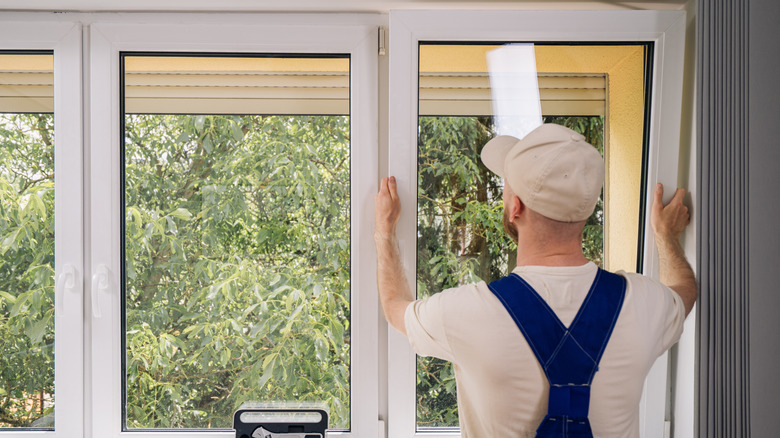 Back view of repairman adjusting system of air ventilation in living room.