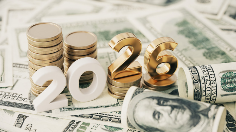 Gold Colored 2026 text and stack coin over 100 American dollar bills.