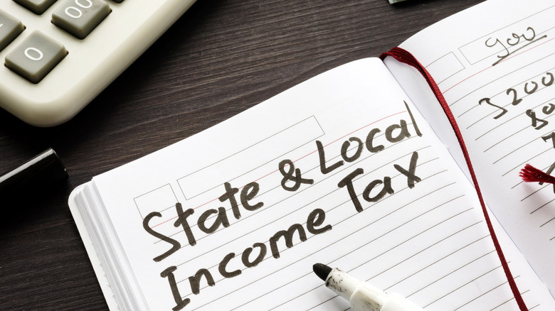 State and local income tax written on notebook with marker with a calculator