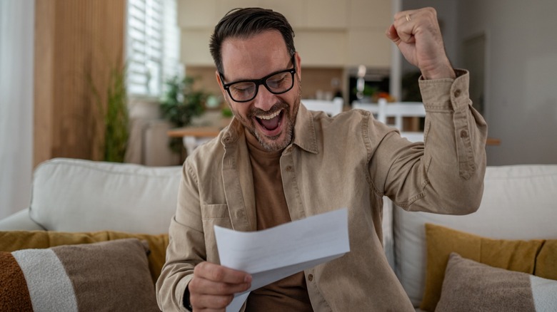 Man reading letter, smiling, with a fist in the air