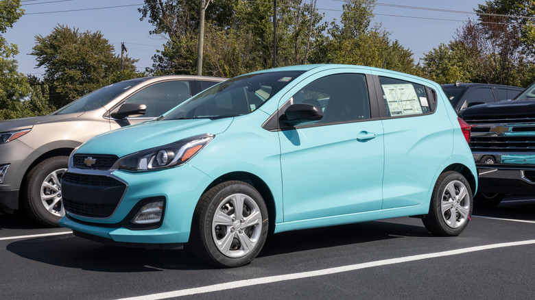 An aqua Chevy Spark at dealership lot