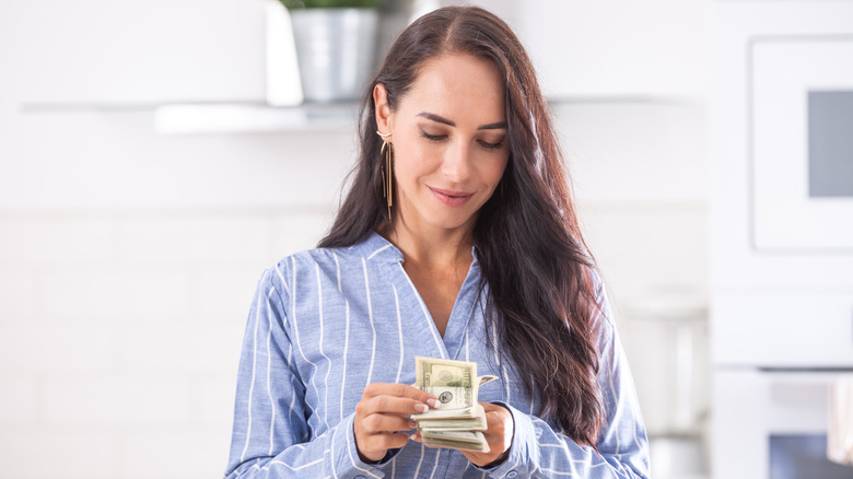 A smiling woman counting money in her hands.