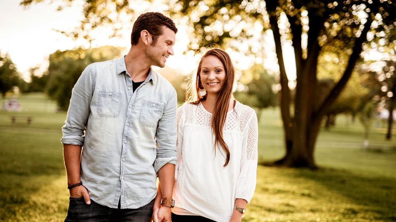 Couple holding hands with tree in the background