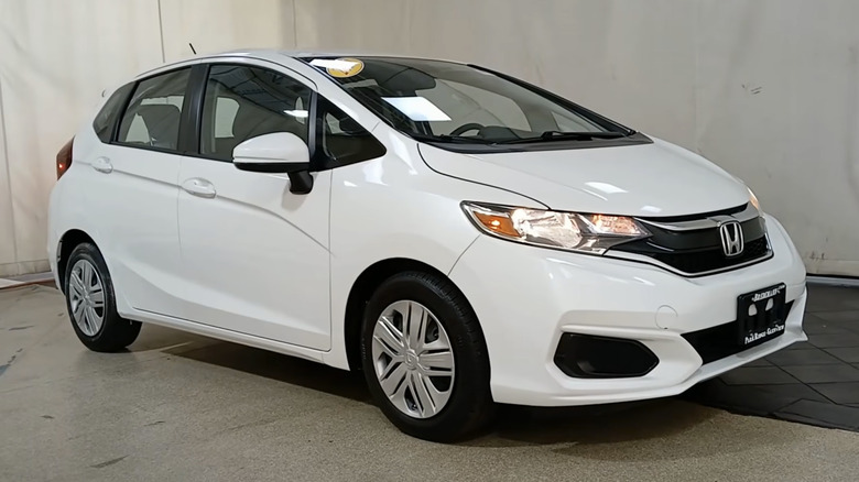 A white 2020 Honda Fit LX on display in a dealership with a 2020 sticker in the window