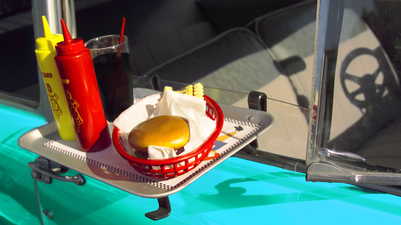 Fast food on drive-in tray on a vintage car