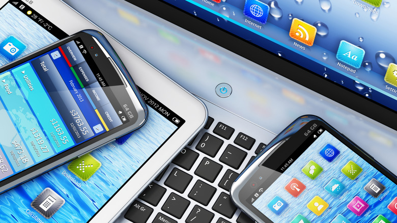 Phones and tablets stacked on a laptop.