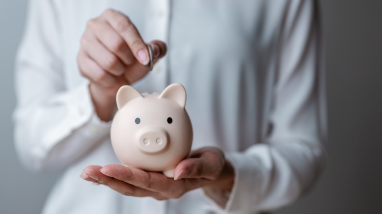 Person putting coin in piggy bank