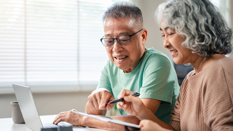 An older couple making plans with a notebook and computer
