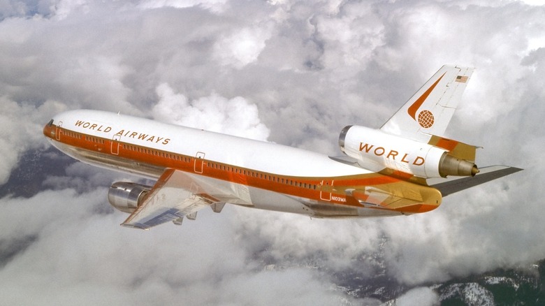 A World Airways flight in the 1970s flying over clouds.