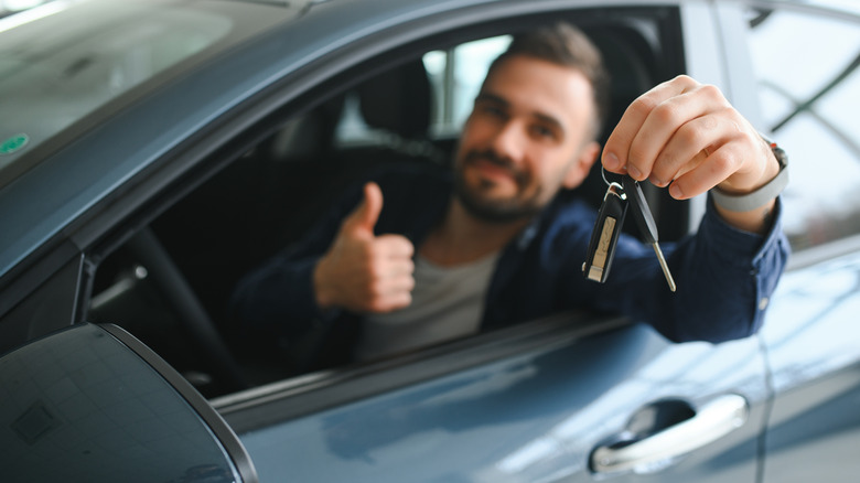 man holding keys and giving a thumbs up