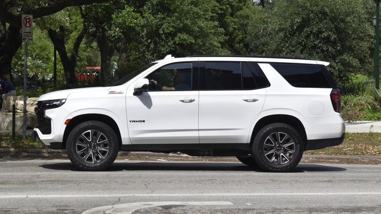 A driver-side view of a white Chevrolet Suburban on the road