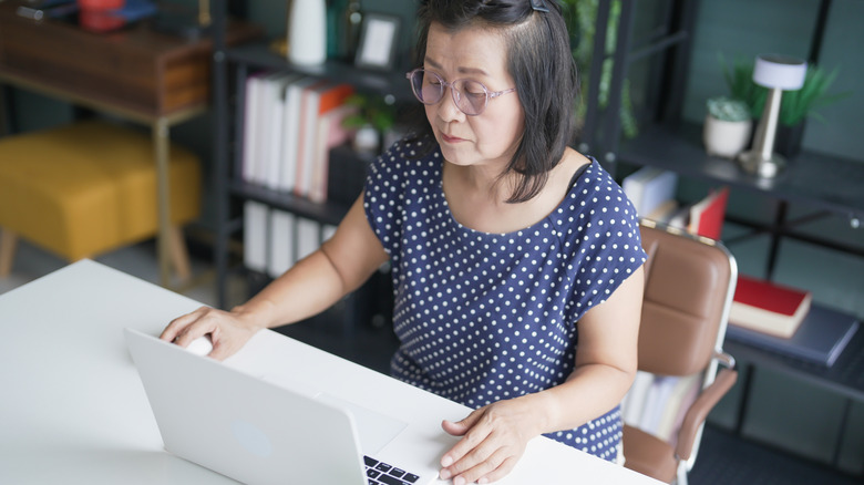 Woman looking at laptop while seated at desk.