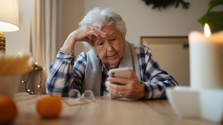 Old women anxiously looking at phone.