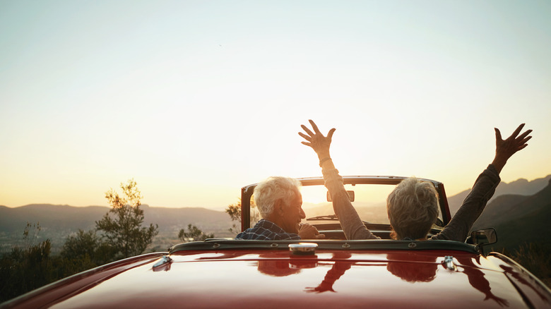 Senior couple driving in a red convertible