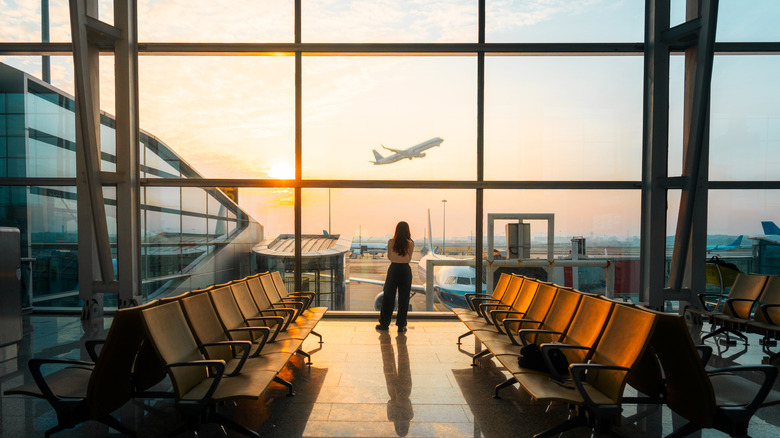 Person watches plane take off at airport.