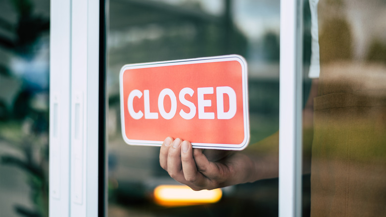 Retail worker placing a "closed" sign in window