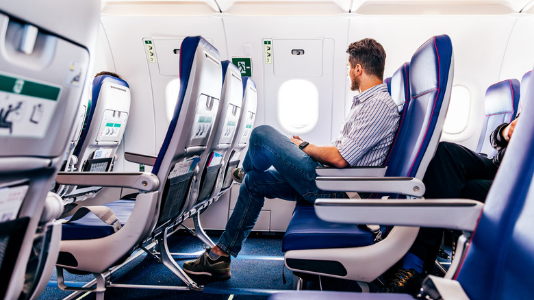 Male passenger sitting middle seat on row of airplane