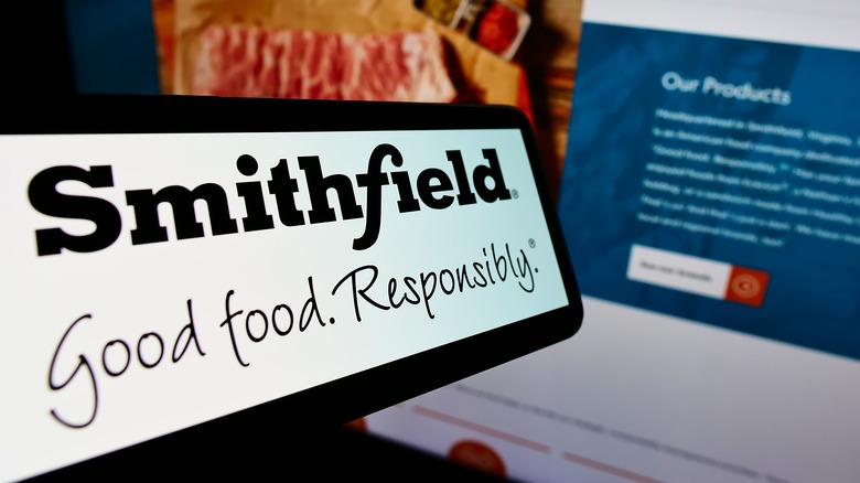 Cellphone with logo of US food processing company Smithfield Foods Inc on screen in front of website Focus on center-right of phone display