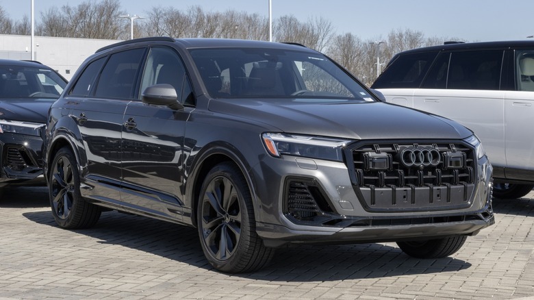 Gray Audi Q7 parked outdoors in a dealership lot, shown from a front three-quarter angle with its grille and LED headlights visible