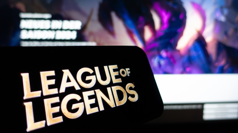 "League of Legends" open on a phone with blurred gaming images in the background