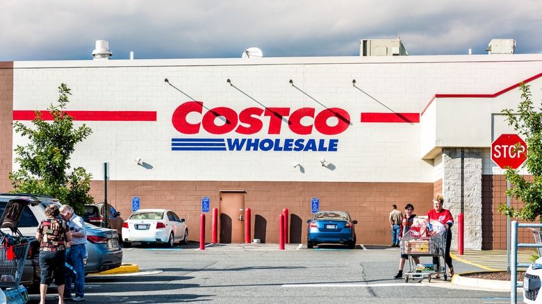 Customers entering and leaving a Costco store on a sunny day