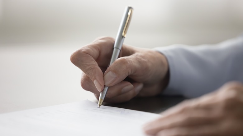 Hands writing with a pen