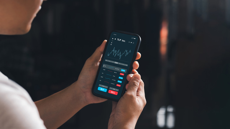 young man checks stock values on a smartphone