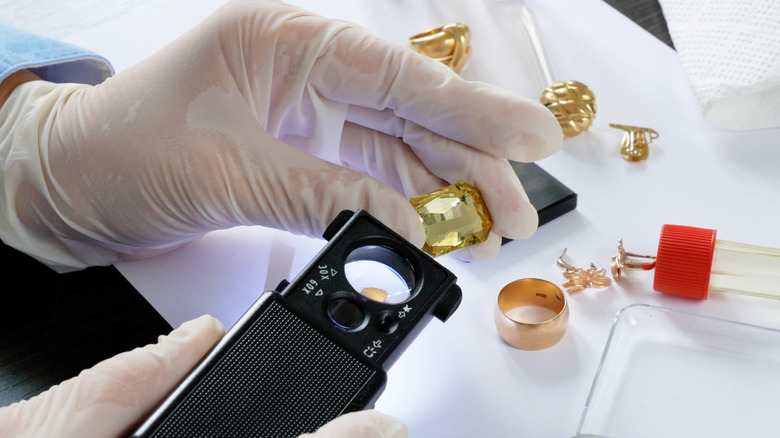 Pawn shop employee testing old gold jewelry