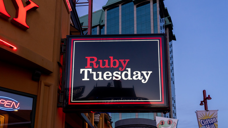 A square Ruby Tuesday sign hangs on the side of the restaurant