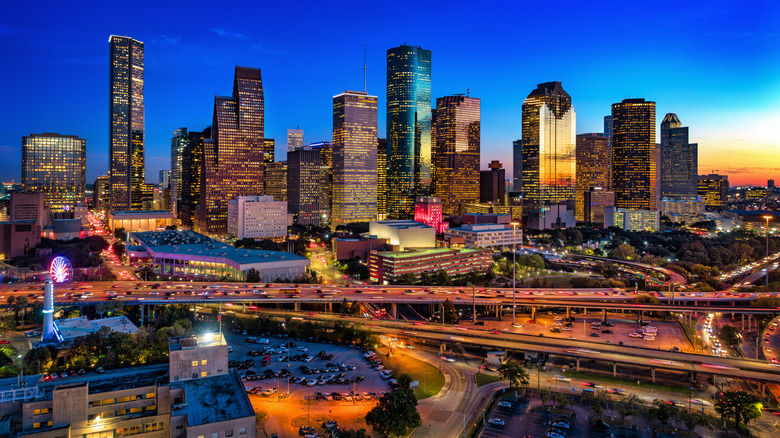 An elevated aerial view of Downtown Houston skyline at dusk with sunset reflections.