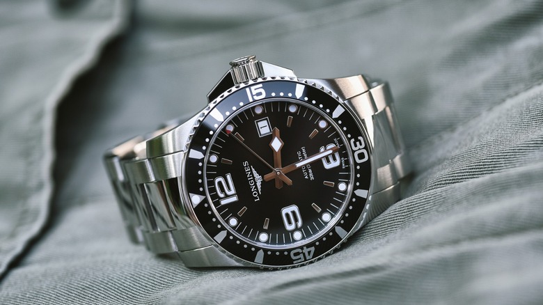 Close-up of a stainless steel Longines HydroConquest dive watch with a black dial and bezel, resting on a light fabric surface