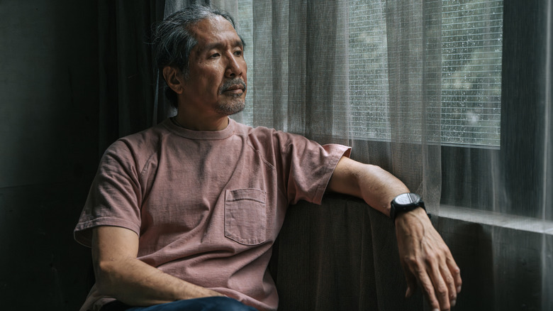 older man looking forlorn by a window