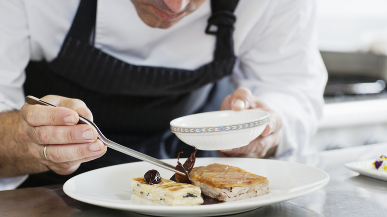 Chef plating food on elegant dish in kitchen