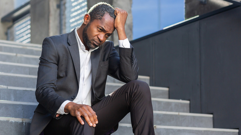 wealthy, middle-aged executive looking stressed outside an office building