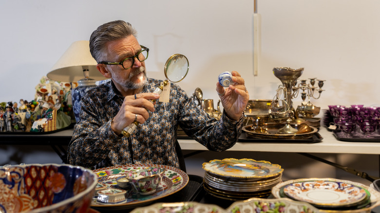 Man looking at collectibles with a magnifiying glass