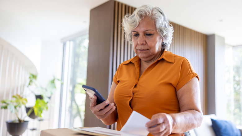 An senior-age woman going through her mail and checking her phone