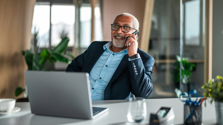 A smiling older man taking a call in an office