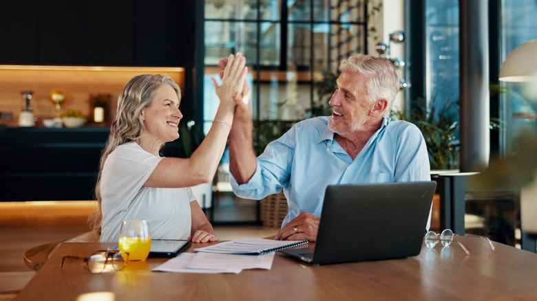 Older couple high-fiving in a kitchen
